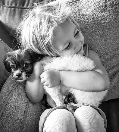 A young girl lovingly hugs her new puppy 