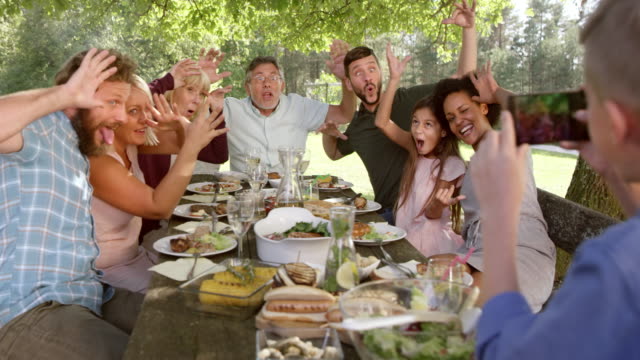 SLO MO Boy taking a funny picture of his family at a picnic