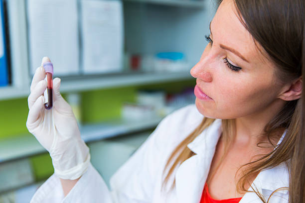 Cute young woman doctor holding vial with blood sample Cute young woman doctor holding vial with blood sample blood bank stock pictures, royalty-free photos & images