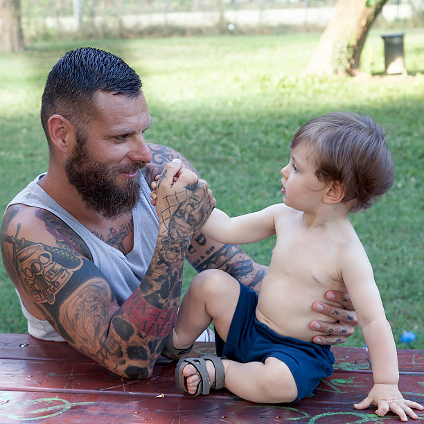 istock tattooed father have fun with his son in the park 623591192