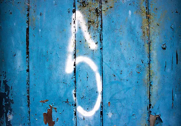 A white spray-painted 5 on a bluedoor