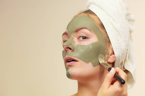 istock Woman applying with brush clay mud mask to her face 623604656