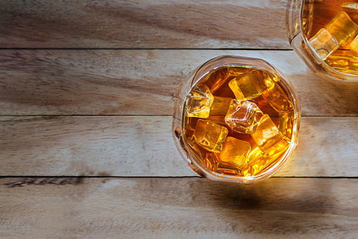 Glass of whiskey with ice on wooden background, Top view and blank text