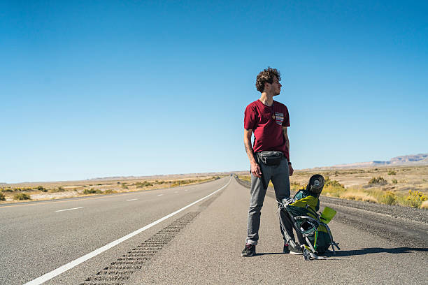 istock Young man, hitchhiker, looking for ride on highway, Utah desert 623606486