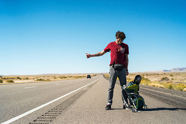 istock Young man, hitchhiker, looking for ride on highway, Utah desert 623606494