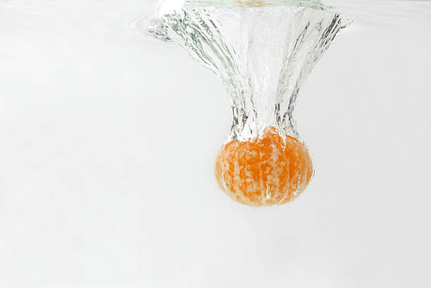 peeled citrus orange falling in water