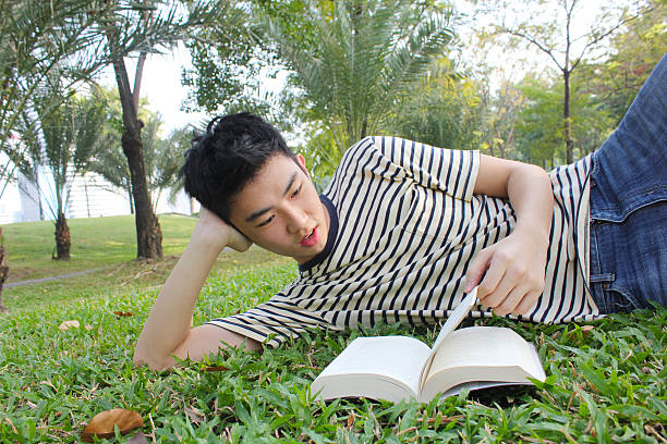 istock Young man reading the book in the park 623607500