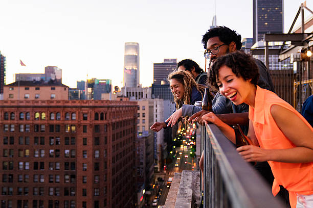 Group of friends hanging out together Group of friends hanging out together on a balcony in downtown Los Angeles, looking over the side down towards the street. Los Angeles, America. October 2016. urban lifestyle stock pictures, royalty-free photos & images
