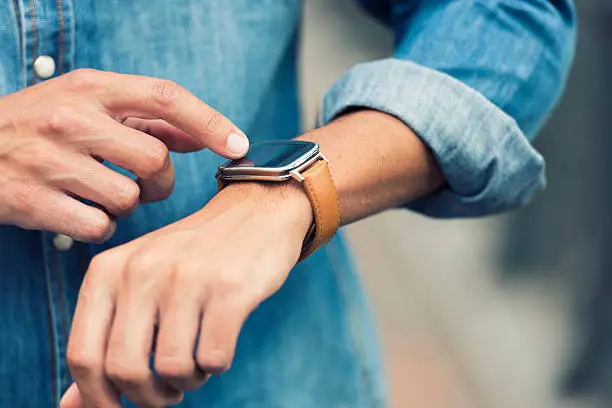 Handsome male in the city using his smart-watch app. Urban background