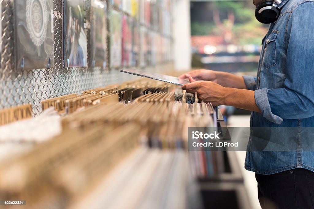 Uomo che sfoglia l'album in vinile in un negozio di dischi - Foto stock royalty-free di Disco - Audio analogico