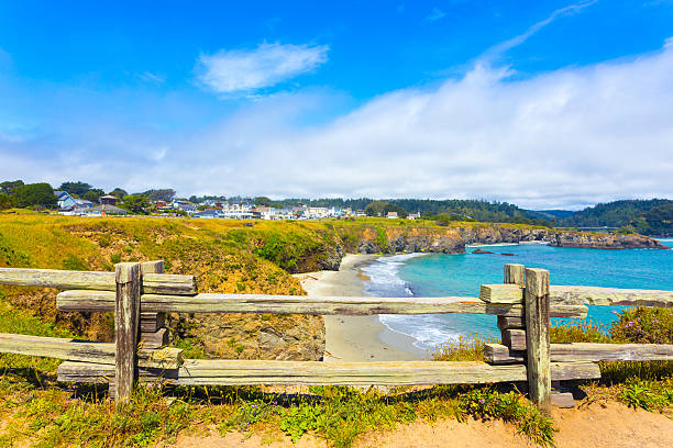Mendocino Town Main Street Beach View H View through rustic wooden fence of sand beach below Main Street and houses of Mendocino town communinty on a sunny summer day in California. Horizontal mendocino photos stock pictures, royalty-free photos & images