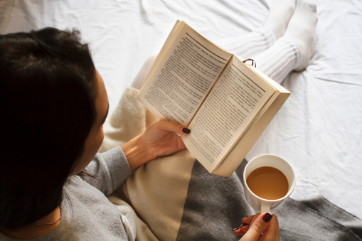 chica leyendo libro y tomando café en la cama por la mañana photo