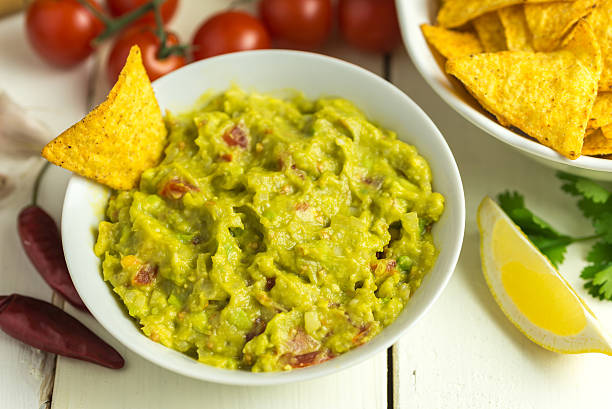 istock Guacamole in white bowl on white wooden desk. 623666590