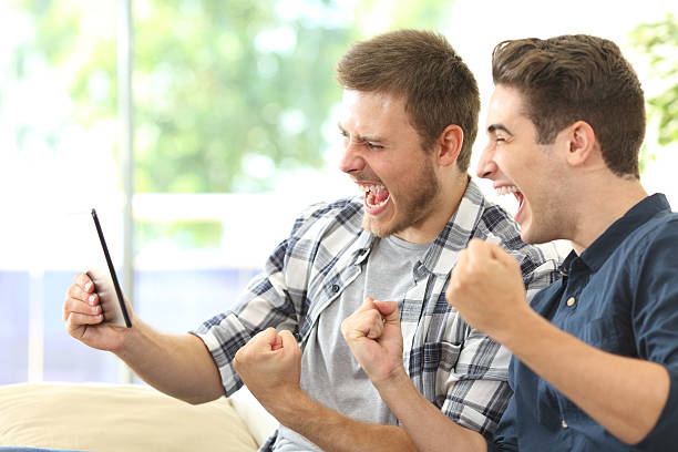 amigos emocionados viendo la televisión en una tableta - video game child handheld video game little boys fotografías e imágenes de stock