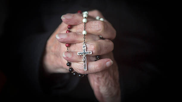 istock old hands praying and holding a rosary 623667728