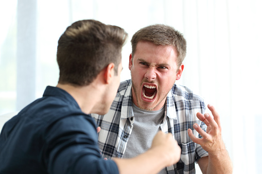 Two angry friends or roommates arguing and threatening in the living room at home