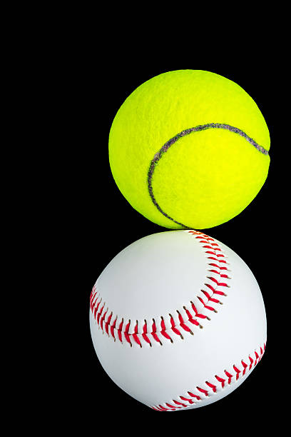 istock ball over black baseball and tennis collide against each other 623676816