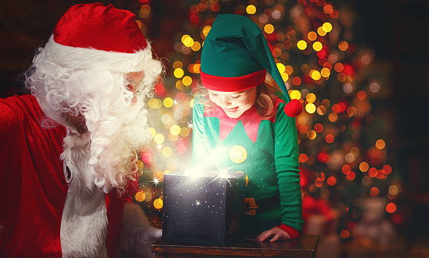 istock Santa Claus and helper child elf with bright magical gift 623680582