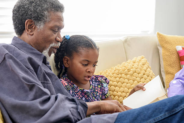 avô afro-americano ouvindo menina ler livro - listening child grandfather family - fotografias e filmes do acervo