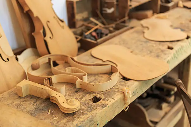 Photo of Unfinished violin and wooden tools in workshop