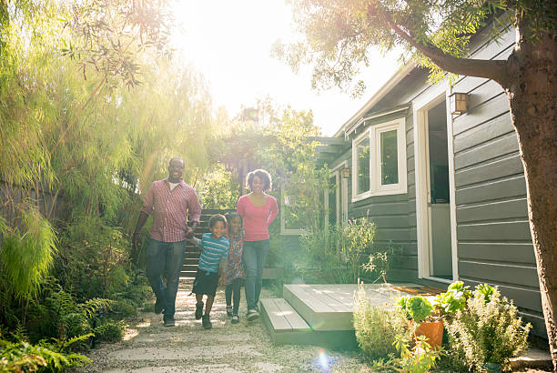 parents afro-américains avec deux enfants marchant dans le jardin - family house flash photos et images de collection