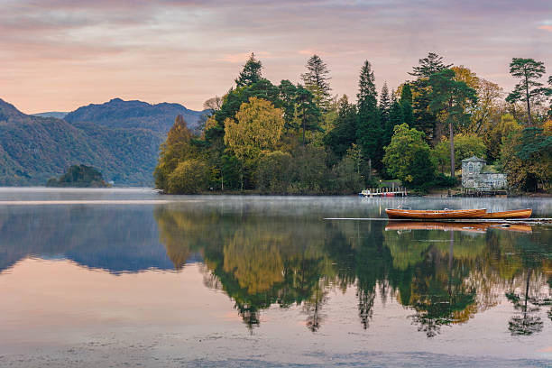Autumn Morning At Derwentwater Lakeside. Wooden rowing boats with mountains and Autumn trees in background at Derwentwater in the English Lake District. keswick stock pictures, royalty-free photos & images