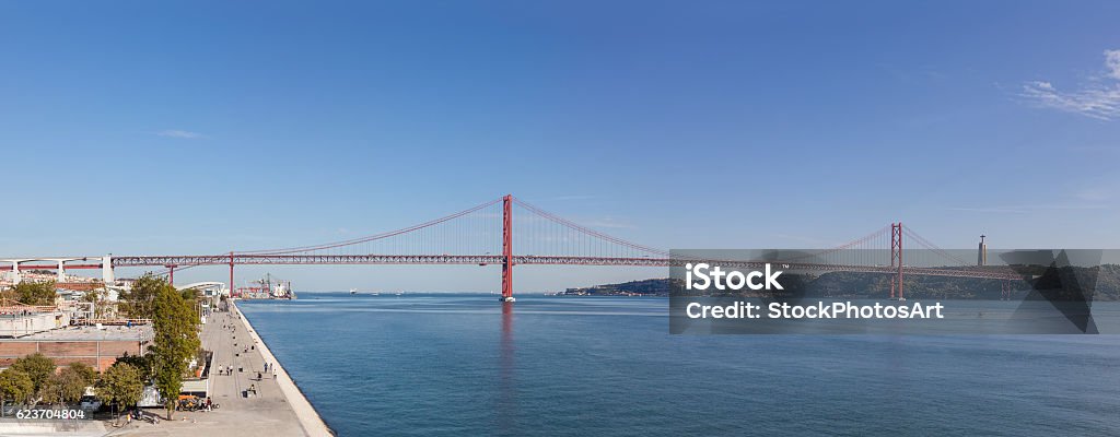 25 de Abril bridge spanning over the Tagus River. Lisbon. Lisbon, Portugal. The 25 de Abril bridge spanning over the Tagus River seen from the Belem District. On the right it’s seen the famous the Cristo-Rei Sanctuary. April 25th Bridge Stock Photo