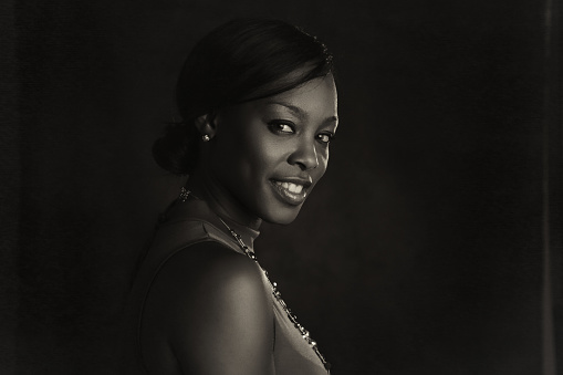 A grayscale portrait of a smiling woman sitting by a pool