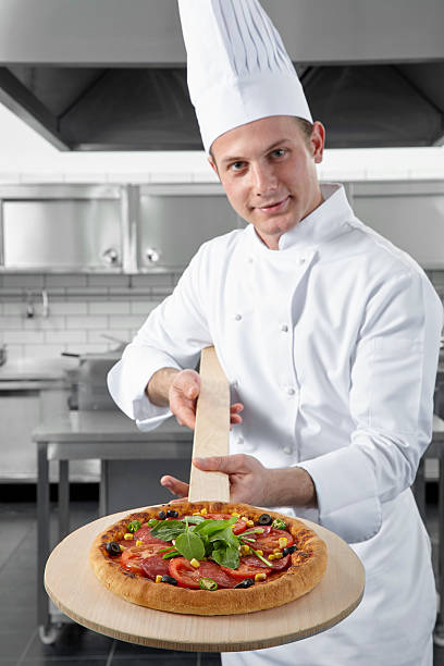 istock Chef offering the pizza on a wooden paddle 623705314