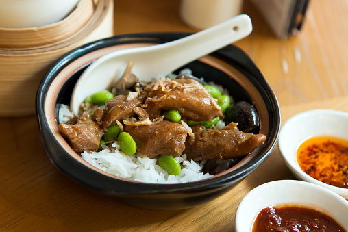 Close up of claypot chicken rice served with mushroom and green peas