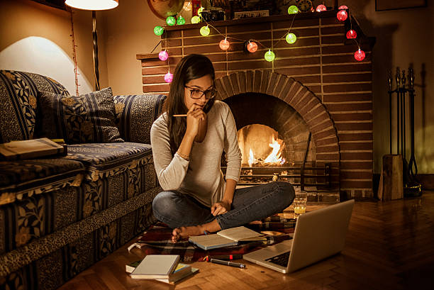 young woman studying at home sitting next to the fireplace
