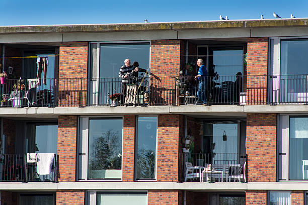 Utrecht, The Netherlands - Octoberber 31, 2016: Two elderly people are talking to each other at the neigbouring balconies of their appartment building in the new suburb Leidsche Rijn.