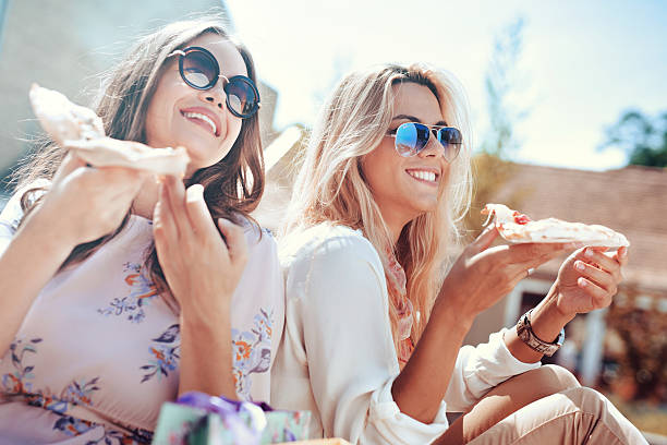 istock Two young women eating pizza outdoors 623706954