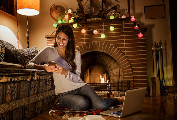istock young woman using her smartphone sitting next to the fireplace 623707514