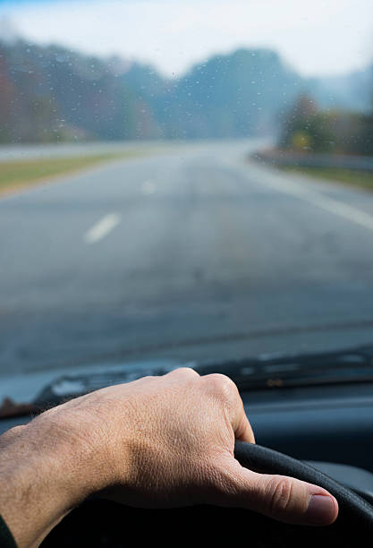 mano del conductor en el volante con fondo de carretera - autopista de cuatro carriles fotografías e imágenes de stock