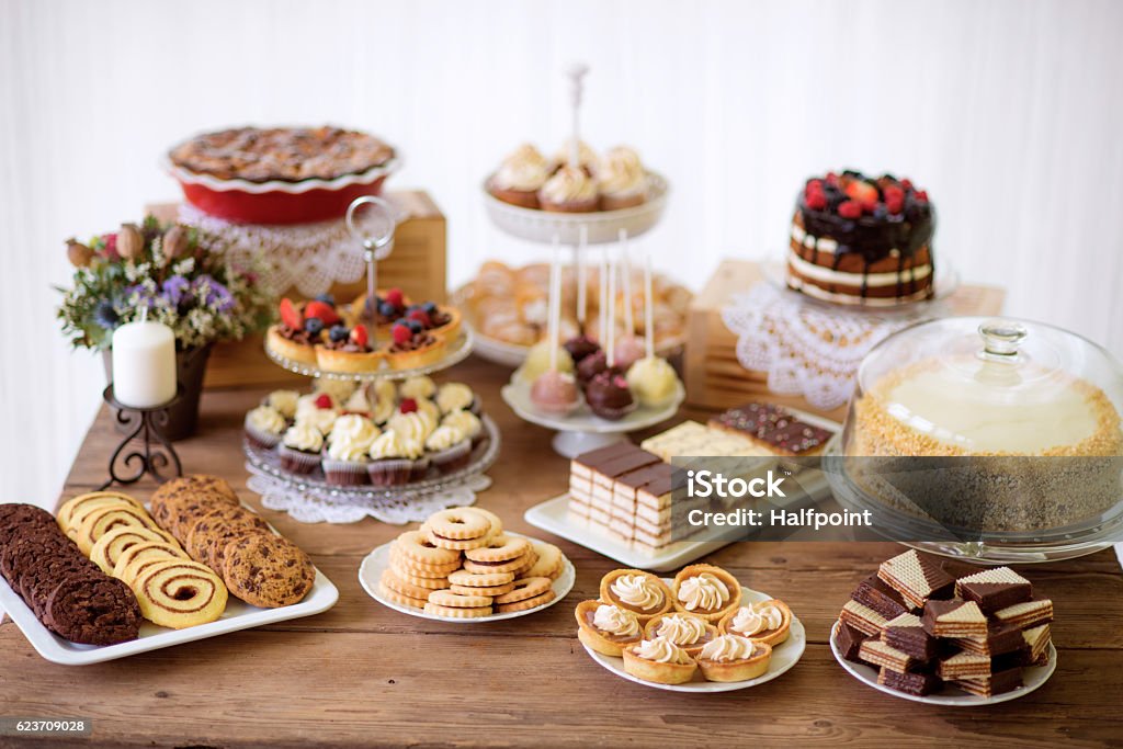 Table with various cookies, tarts, cakes, cupcakes and cakepops Brown wooden table with various cookies, tarts, cakes, cupcakes and cakepops. Studio shot. Cake Stock Photo