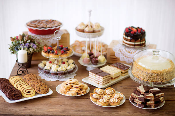 Table with various cookies, tarts, cakes, cupcakes and cakepops Brown wooden table with various cookies, tarts, cakes, cupcakes and cakepops. Studio shot. tart dessert stock pictures, royalty-free photos & images