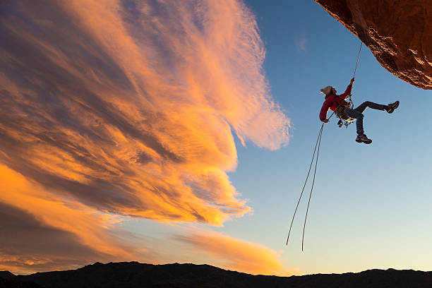 Climber on rappel. Female climber rappelling down a sheer cliff. adrenaline stock pictures, royalty-free photos & images