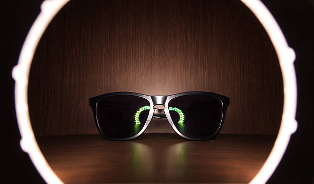 black Sunglasses on wood floor with led ring light reflect