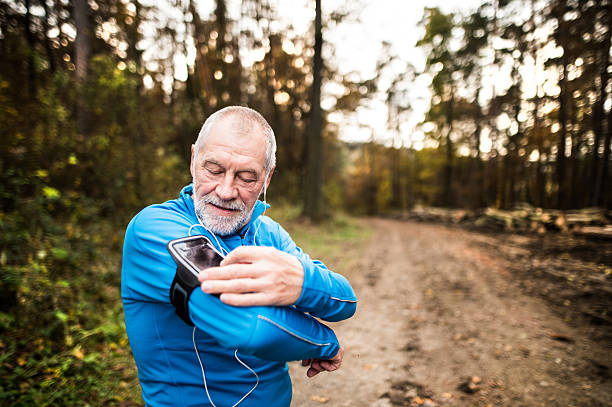 senior läufer in der natur mit smartphone und kopfhörer. - telephone nature mobile phone autumn stock-fotos und bilder