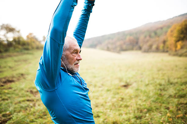 istock Senior runner with earphones doing stretching. Autumn nature. 623742468
