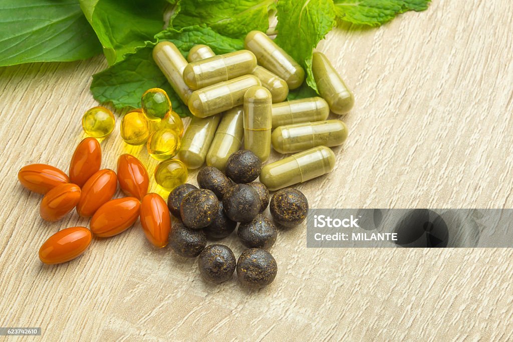 Medicine herb Herbal pills with healthy medical plant. Green leaf, alternative drug on wood ground Nutritional Supplement Stock Photo