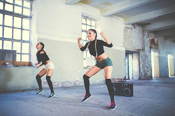 athletic young women exercising together and looking at camera on grey