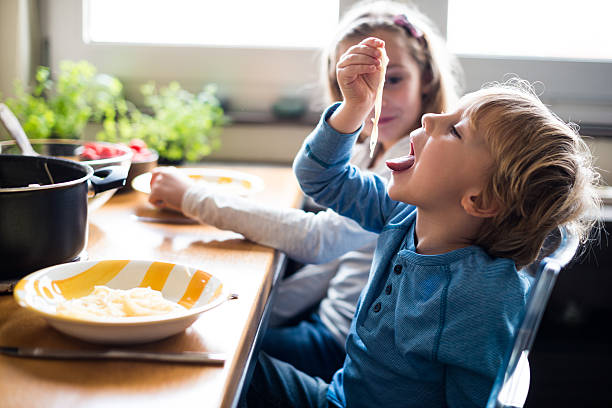 Enjoying pasta time Kids having fun while enjoying lunch time. kids eating noodles stock pictures, royalty-free photos & images