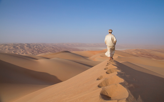 Hombre en kandura en un desierto al amanecer photo
