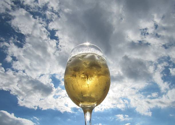Two wine glasses with white wine served with olives on outdoor terrace witn blue sea and mountains view on background in sunny summer day