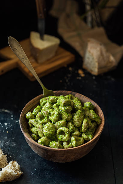 wooden bowl full of dumplings with pesto and fork upright wooden bowl full of dumplings with pesto and fork upright lavagna stock pictures, royalty-free photos & images