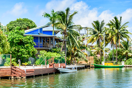 Placencia, Belize - August 28, 2016: Tropical waterside house with moored boats on lagoon side of Placencia in Belize, Central America