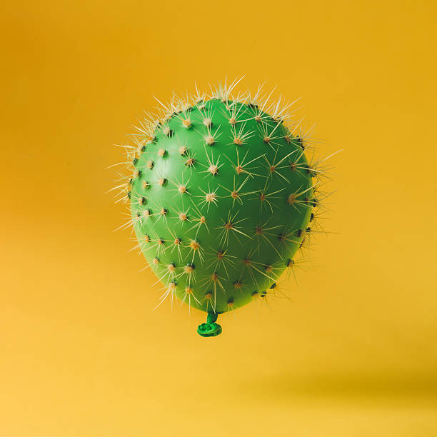 Balloon with cactus needles on bright yellow background. Creativ