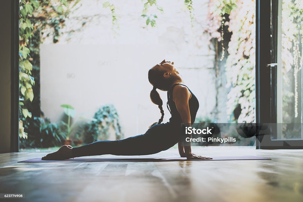 Portrait of gorgeous young woman practicing yoga indoor. Beautiful girl Portrait of gorgeous young woman practicing yoga indoor. Beautiful girl practice cobra asana in class.Calmness and relax, female happiness.Horizontal, blurred background Yoga Stock Photo